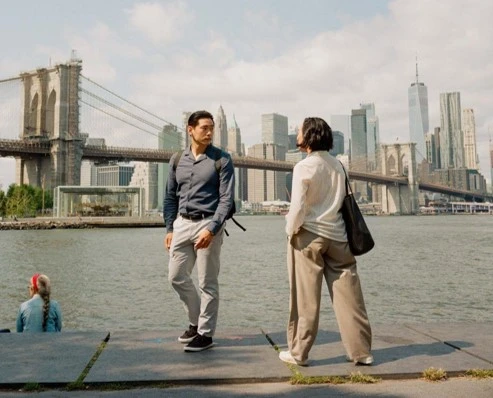 A man and a woman look at each other with New York's skyline in the background. 