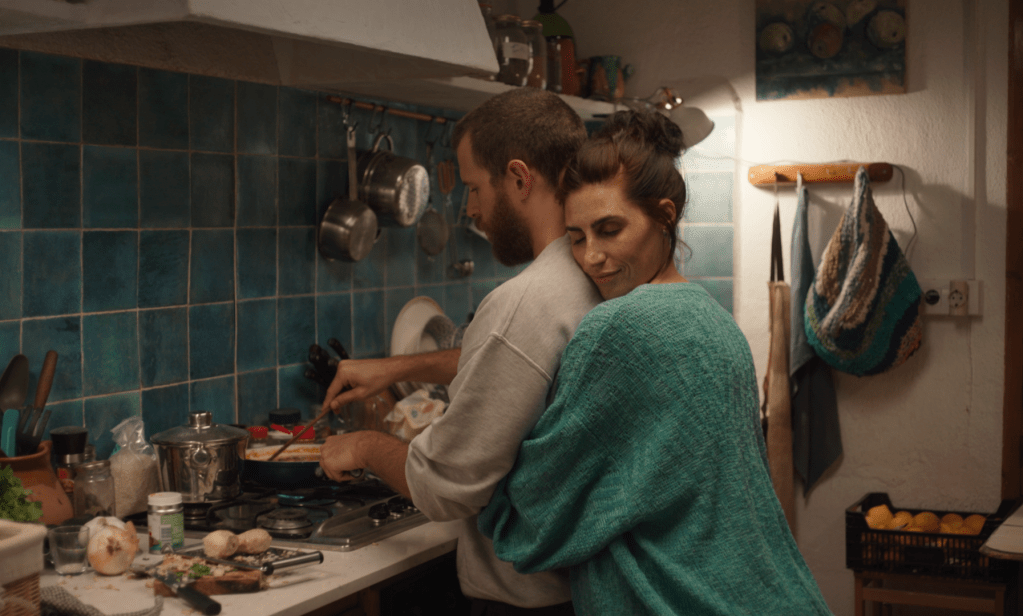 A woman hugging a man as he cooks