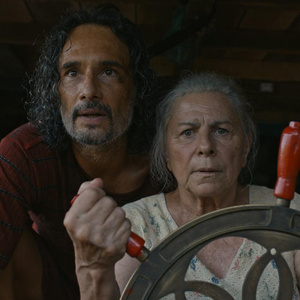A man stands behind a woman steering a boat